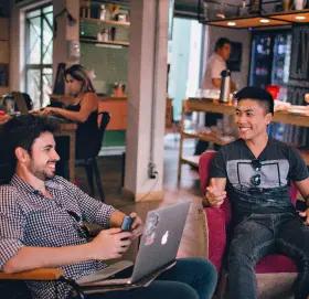 Dois homens sentados na empresa, sorrindo um para o outro